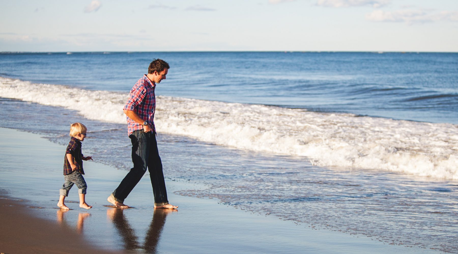 A father and child walking along the beach